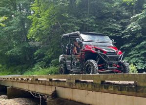 A happy family sitting in a 4-seater UTV rental, showing the easy-to-use steering wheel and automotive-style seats