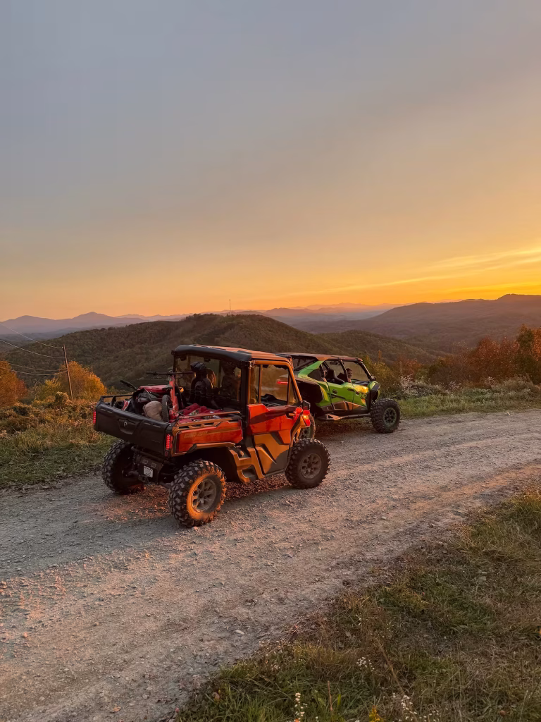 A group of adventurers in a four-seater Can-Am Defender UTV pause on a Smoky Mountain trail peak at sunset during a self-guided rental with Off-Road Gatlinburg.